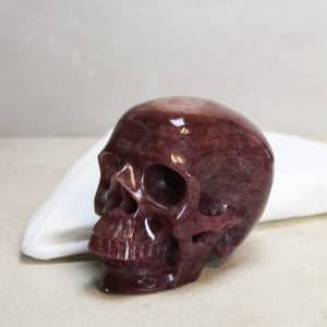 Skull van Cherry kwarts  Elke Skull uit onze collectie is een meesterwerk van de natuur (en de slijper).  De schedelvorm, symbool van wijsheid en kennis, is samengevoegd met de helende en opbeurende eigenschappen van Cherry kwarts. Een kristallen doodskop wordt vaak gezien als krachtige beschermer en kan helpen bij heling en het brengen van levensvreugde.