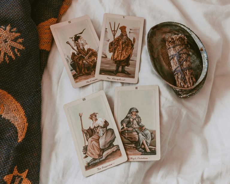 Ben je nieuwsgierig naar tarotkaarten en wil je ontdekken hoe ze jouw leven kunnen verrijken? Tarot is een eeuwenoude praktijk die inzicht, begeleiding en zelfontdekking biedt. In deze blogpost nemen we je mee op een reis door de fascinerende wereld van tarot en hoe je kunt beginnen. Tarot bestaat uit een set van 78 kaarten, verdeeld in de Grote Arcana (22 kaarten) en de Kleine Arcana (56 kaarten). Elke kaart heeft unieke symbolen en betekenissen die inzicht kunnen geven in verschillende aspecten van je leven. De Grote Arcana-kaarten vertegenwoordigen belangrijke levensgebeurtenissen en spirituele lessen, terwijl de Kleine Arcana-kaarten zich richten op dagelijkse gebeurtenissen en uitdagingen. Wil jij weten hoe je kunt starten met tarot? Lees dan vooral mee! Hoe begin je met tarot? 1. Kies een deck: Het vinden van het juiste tarotdeck is een persoonlijke keuze. De populaire keuze voor beginners is het Rider-Waite Tarot, een van de eerste tarotdecks en het deck waar het meest naar gerefereerd wordt in boeken over tarot. Dit kan een handig startpunt zijn wanneer je op onderzoek gaat naar betekenissen. Uiteindelijk blijft het aan jou de keuze of dit deck daadwerkelijk bij jou past. Bekijk daarom verschillende decks en kies degene die jou het meest aanspreekt. 2. Leer de betekenissen: Neem de tijd om de betekenissen van de kaarten te leren. Begin met de Grote Arcana en werk daarna door de Kleine Arcana. Er zijn talloze boeken en online bronnen die gedetailleerde uitleg bieden. Het geeft niet als je niet meteen alle betekenissen weet. Veel tarotleggers grijpen naar hun naslagwerk. Door regelmatig tarot te leggen, leer je steeds meer betekenissen uit je hoofd. 3. Intuïtie ontwikkelen: Tarot is niet alleen een kwestie van betekenissen uit je hoofd leren. Luister naar je intuïtie en de gevoelens die de kaarten oproepen. Dit zal je helpen om diepere en persoonlijkere interpretaties te maken. Bekijk ook de tekeningen van de kaart en kijk of er elementen zijn die je herkent en mogelijk het antwoord op je vraag kunnen geven. 4. Oefen regelmatig: Zoals met elke vaardigheid, geldt ook voor tarot dat oefening kunst baart. Een makkelijke manier om regelmatig met tarot te oefenen is door dagelijks een kaart te trekken en op de boodschap ervan te reflecteren. Dit helpt je om vertrouwd te raken met de kaarten en hun betekenissen. Simpele tarotleggingen Een eenvoudige manier om te beginnen is met een dagkaart. Trek elke ochtend een kaart en vraag jezelf af wat deze kaart jou die dag kan leren. Een andere populaire legging is de Driekaartlegging, waarbij je drie kaarten trekt voor verleden, heden en toekomst. Aan de slag Tarot is een prachtige tool voor zelfontdekking en begeleiding. Door een deck te kiezen dat bij je past, de betekenissen van de kaarten te leren en regelmatig te oefenen, kun je beginnen aan een verrijkende reis. Onthoud, het gaat niet om het voorspellen van de toekomst, maar om het begrijpen van jezelf en je levenspad. Veel succes en plezier op jouw tarotavontuur!